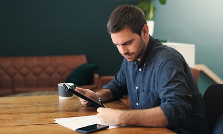 Man at table filing taxes on tablet